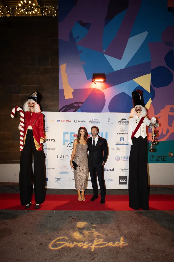 A couple on the red carpet between the nutcracker stilt walkers