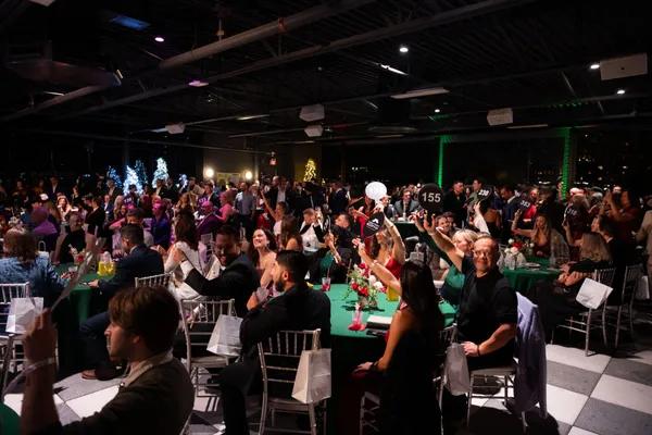 A packed room raising bid paddles during the live auction